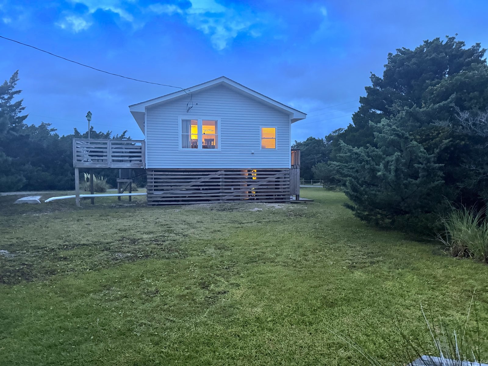 Lucky Landing cottage at dusk with warm lit windows in Avon, Hatteras Island